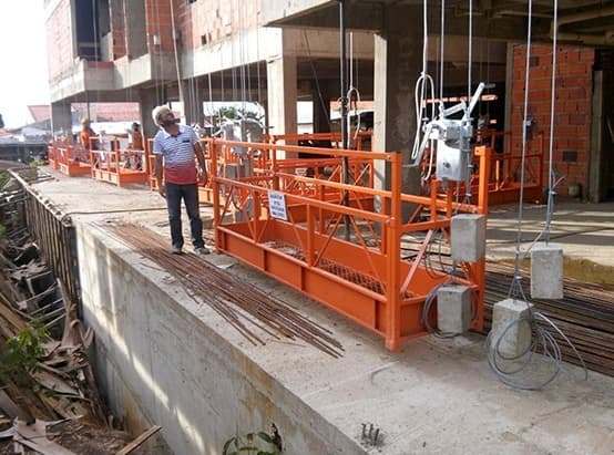 Balancins laranjas de fachada instalados em obra, com placas de identificação de capacidade