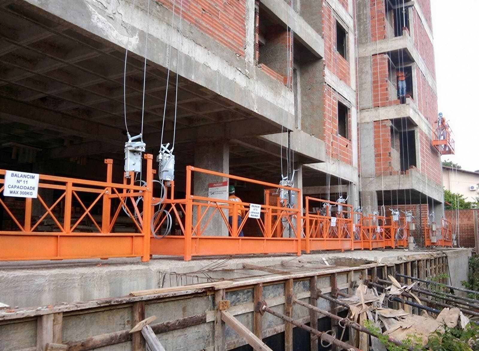 Andaimes suspensos laranjas instalados pela 4M Engenharia em edifício residencial em construção