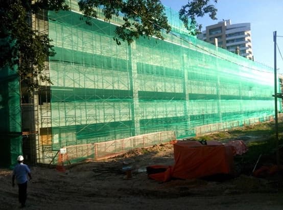Fachada de obra coberta por andaime fachadeiro com tela de proteção verde