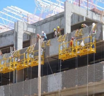 Andaimes suspensos com operários trabalhando em fachada de concreto
