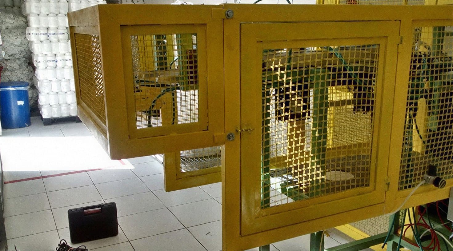 Proteção fixa de máquina em grade metálica amarela instalada conforme NR-12 em ambiente industrial